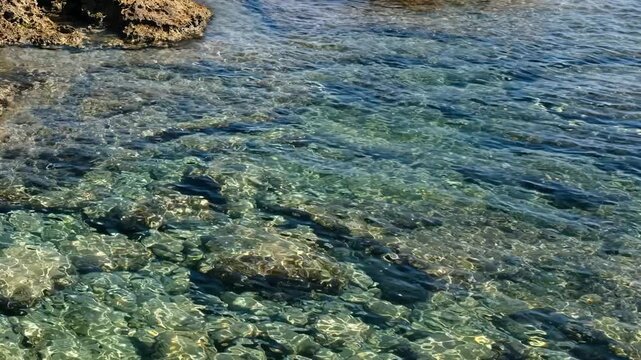 Video of coastal rocks and stones on the bottom with clear Mediterranean sea water. Crete, Greece