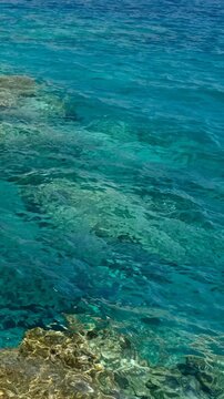 Vertical video of the stones on the bottom under blue clear Mediterranean sea water. Crete, Greece