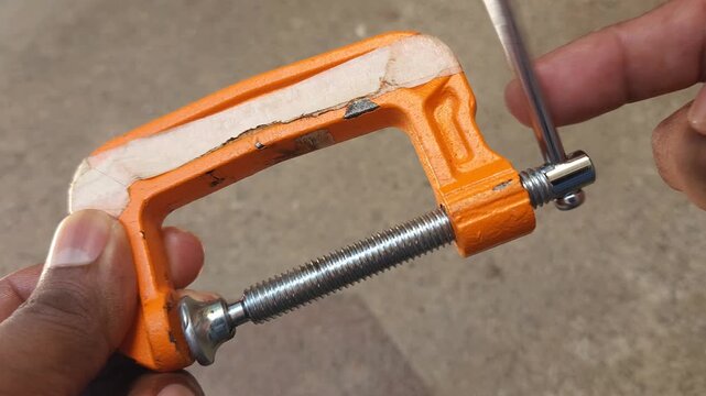 Adjusting Metal C Clamp Fixed on Wooden Base in Workshop