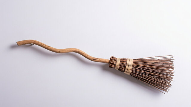A mystical wooden broomstick crafted from a curved branch features tightly bound bristles and serves as a classic accessory for portraying traditional folklore legends or seasonal autumn