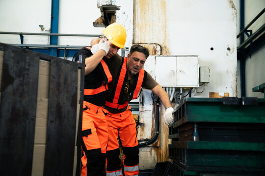 Worker helping an injured colleague after accident in factory