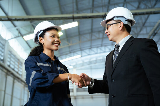 Factory manager congratulating female engineer with successful handshake