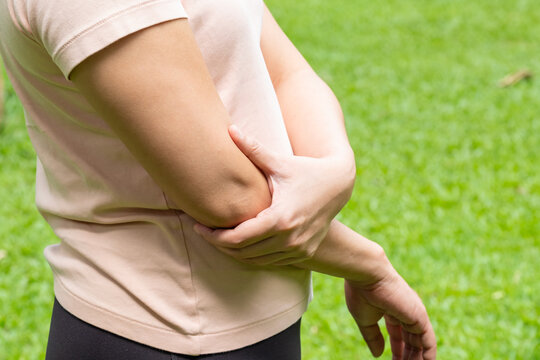 A woman has pain in his elbow and tendon muscles and he relieves the pain with a massage. Health and healing concept	
