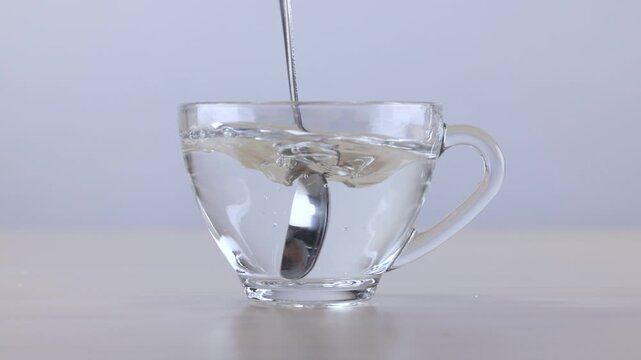 Metal Spoon Stirring Hot Water in Transparent Glass Cup