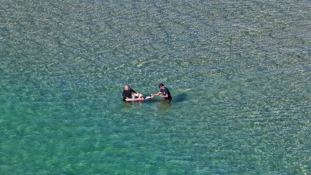 Aerial View of Men Training a Small Dog on a Surfboard