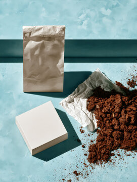 Brown coffee grounds spill from a torn bag