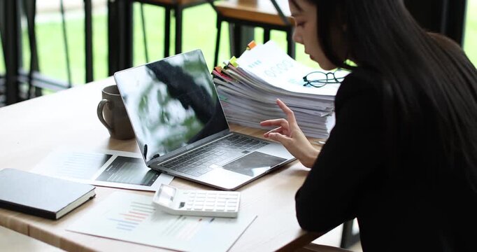Businesswoman analyzing financial reports and working on laptop in modern office, managing business data