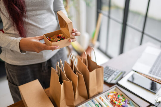 Woman packing customer purchase into paper bag for small business with sustainable packaging and eco friendly retail Green business.