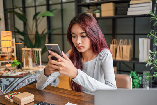 Woman checking ecommerce store with smartphone for online sales customer orders and business management.