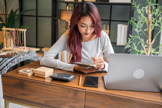 Woman managing small business accounts and recording sales revenue and expenses business income financial management entrepreneurship .