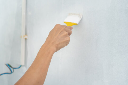 Portrait painter man, brush in hand for products to restore and paint the wall, indoor the building site of a house, wall during painting, renovation, painting, contractor, Architect, construction