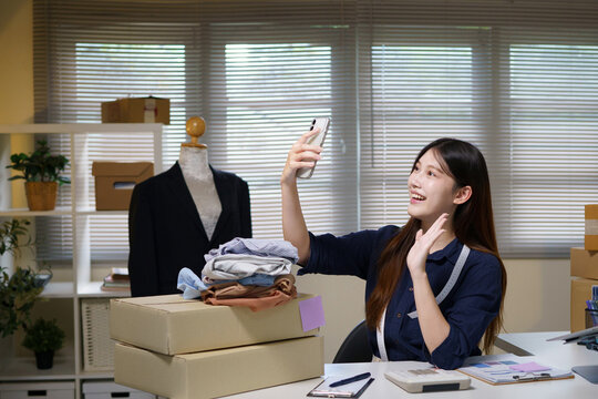 Young Asian Woman Fashion Entrepreneur Taking Selfie with Clothes for Online Store Social Media
