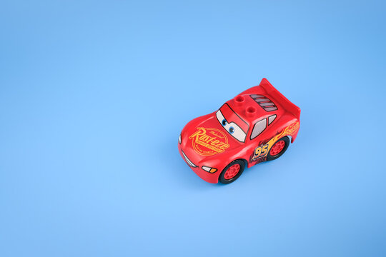 A Lightning McQueen toy car is photographed from a high angle on a light blue background with wide negative space surrounding the miniature vehicle on Jul 25, 2026 in Jakarta, Indonesia.