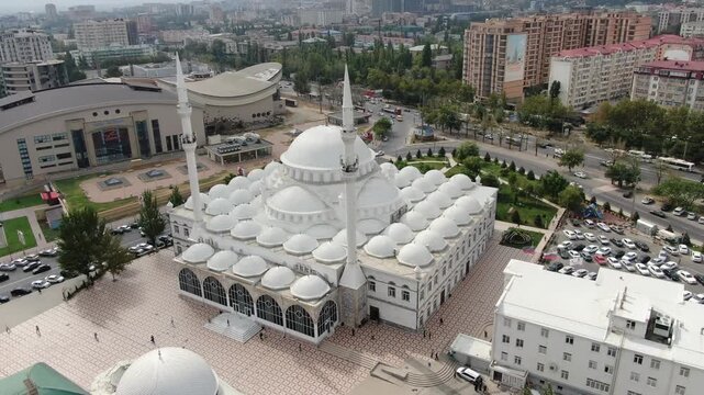 MAKHACHKALA, RUSSIA. AUG 15, 2022: Aerial view of the Grand Central Juma Mosque featuring white domes, tall minarets, and surrounding urban architecture.