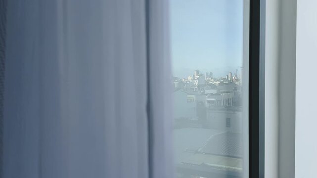Open balcony door with moving in the draught curtain and panoramic city skyline reflection