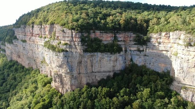 Aerial view of the Eagle Shelf (Polka Orlinaya), a massive sheer rocky cliff covered with lush green forests in Mezmay, Krasnodar Region, Russia.