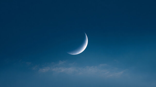 Crescent moon shining bright in deep blue evening sky