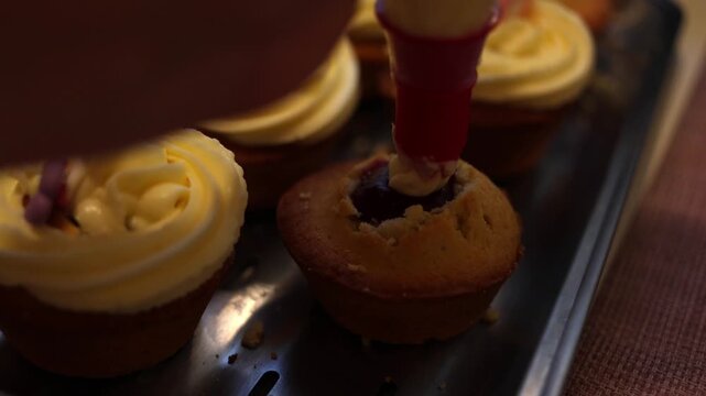 A pastry chef skillfully decorates cupcakes with smooth white frosting using a piping bag, creating an exquisite dessert in a bustling professional kitchen filled with mouth-watering aromas. Slow moti
