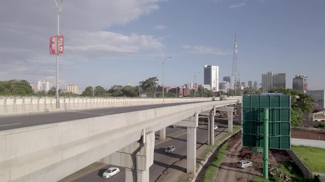 Aerial drone reveal medium wide shots of the Nairobi Expressway with a truck passing through the screen and vehicles below on Uhuru highway showing difference in traffic