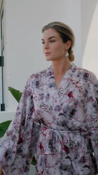Elegant woman wearing luxury kimono robe in modern tropical home.