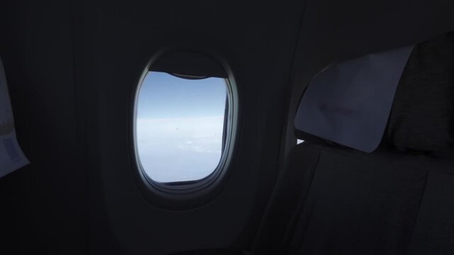 view from inside flying aircraft plane with seated in economy class and plane's window with view of mountain range and clear blue sky in winter time,traveling flying airplane vacation background