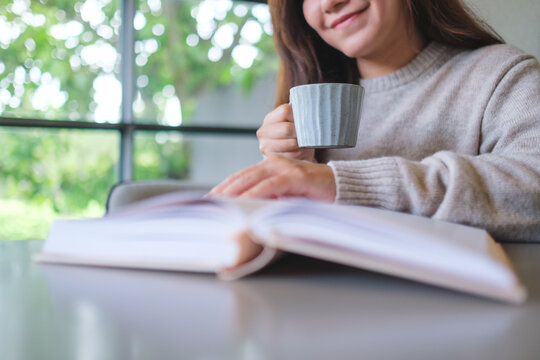 Closeup image of a woman reading a book and drinking coffee