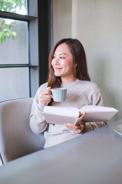 Vertical portrait image of a woman reading a book and drinking coffee