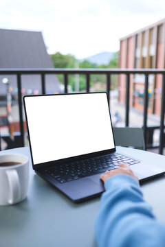 Vertical mockup image of a woman working on laptop computer with blank white desktop screen in cafe