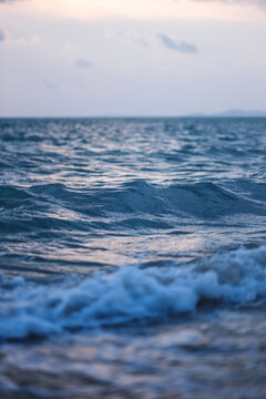 Vertical landscape image of sea wave splashing on beach before sunset