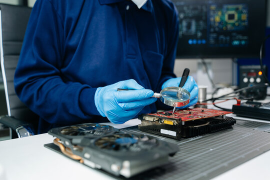 Professional technician wearing protective gloves inspecting a GPU graphics card at a hardware repair workbench. Ideal for building and tech service themes.