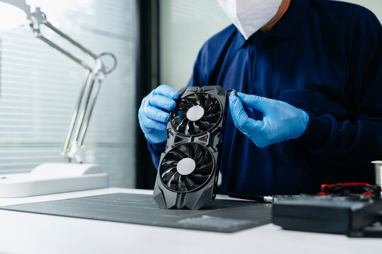 Professional technician wearing protective gloves inspecting a GPU graphics card at a hardware repair workbench. Ideal for building and tech service themes.