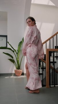Elegant woman wearing luxury kimono robe in modern tropical home.