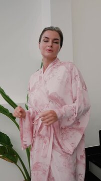 Elegant woman wearing luxury kimono robe in modern tropical home.