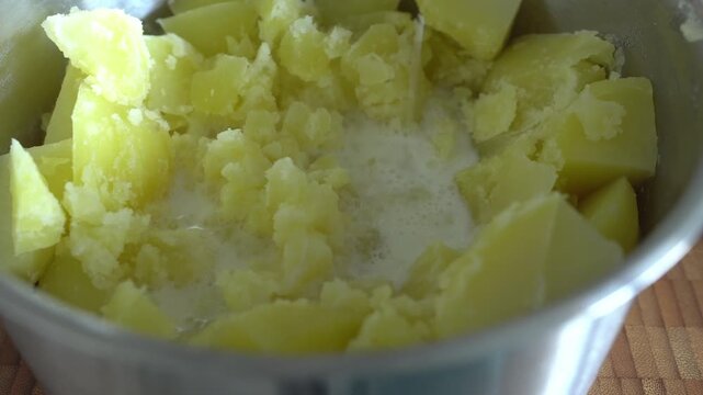 The process of making mashed potatoes. Milk is poured into boiled potatoes. Recipe.