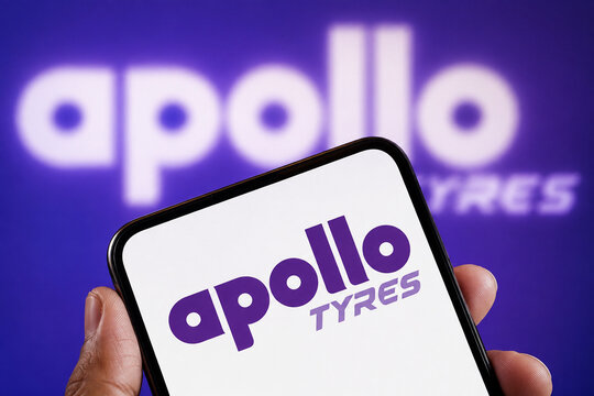 Illustrative editorial concept of the Apollo Tyres logo on a tilted handheld smartphone against a purple corporate background with an enlarged blurred wordmark.