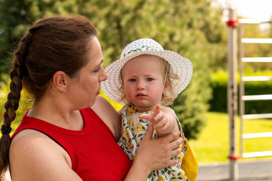 Toddler Girl Points Ahead While Mother Holds Her