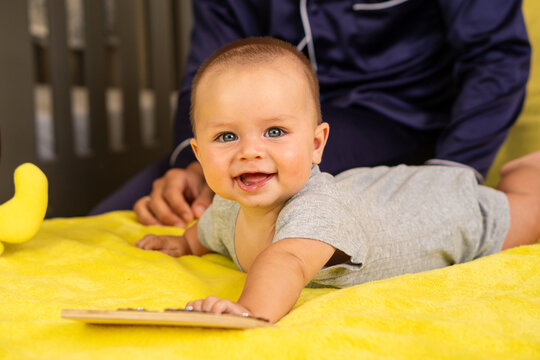 Smiling Baby During Tummy Time With Caregiver Nearby