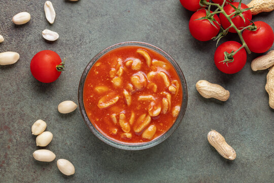 Peanuts in tomato sauce in glass bowl on the table. Top view