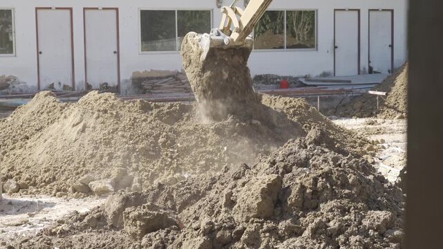 view to excavator while working scoop digging a trench and removing soil in the field at construction site in sunny day,excavator bucket shoveling dirt in field soil site