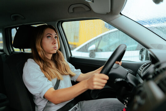 Stressed Beginner Woman Driving Car In Heavy Rain Outside Weather. Anxious female student driver grips steering wheel feeling panicked during dangerous rainy commute