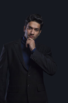 Confident young businessman with his hand on chin