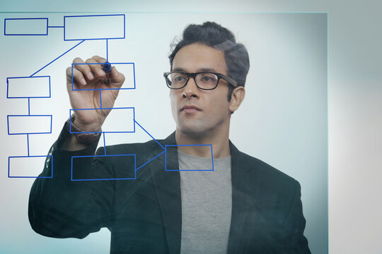 Businessman drawing an empty flowchart on glass