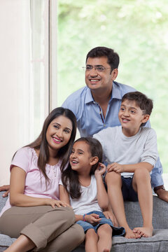 Portrait of family with two children sitting sofa together