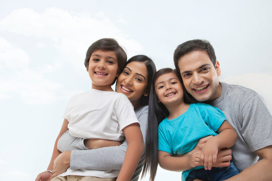 Portrait of a happy family looking at the camera against sky and clouds