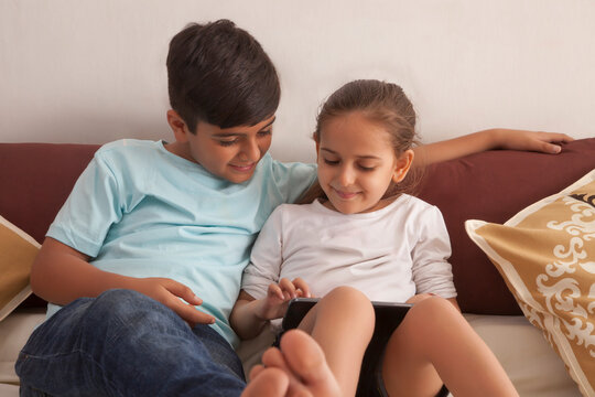 Brother and sister playing video game on digital tablet