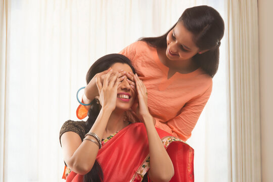 Close-up of a teenage daughter covering her mother's eyes