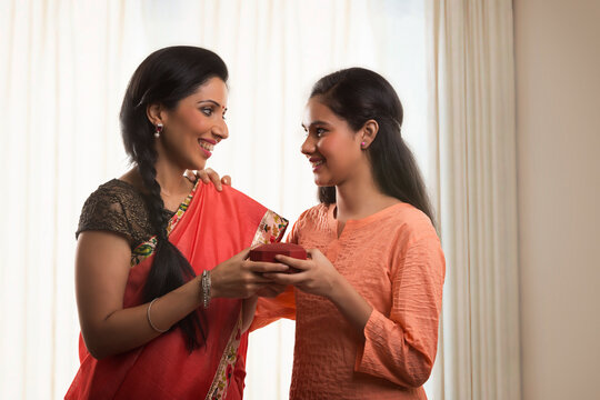 Indian mother and daughter holding gift jewelry box