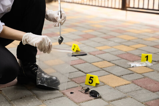 Forensic expert collecting evidence at a crime scene, criminal investigation and law enforcement concept, a forensic expert in white gloves collects evidence at a crime scene
