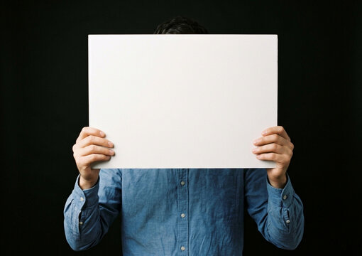 Person holding a blank sign against a black background