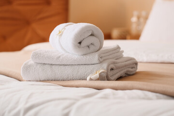 Fototapeta premium Stack of clean white towels with a decorative flower on a hotel bed, hospitality and comfort concept, this arrangement suggests a relaxing spa experience or a welcoming guest room